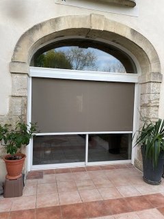 Store ZIP sur mesure à Saint-Saturnin-lès-Avignon — coffre intégré dans les montants du coulissant, encadrement en pierre préservé. Protection solaire extérieure jusqu'à 95 % du rayonnement sur un mas provençal de 1830.